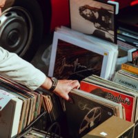 Homme fouillant dans un bac de vinyle dans une brocante