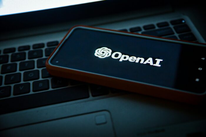 téléphone posé sur un ordinateur portable, avec l'application OpenAI ouverte.